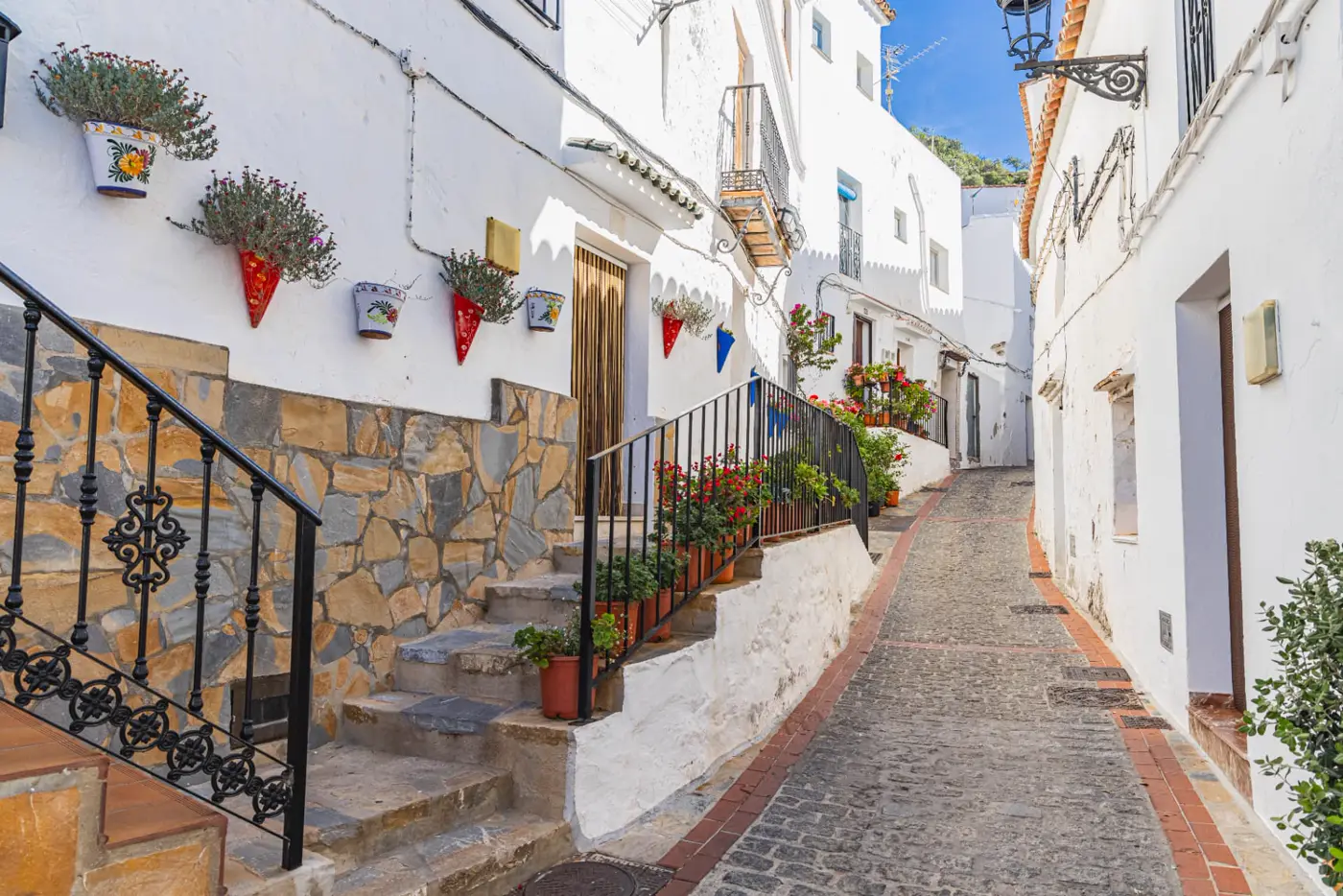 Whitewashed cobbled street with flower pots in Casares village