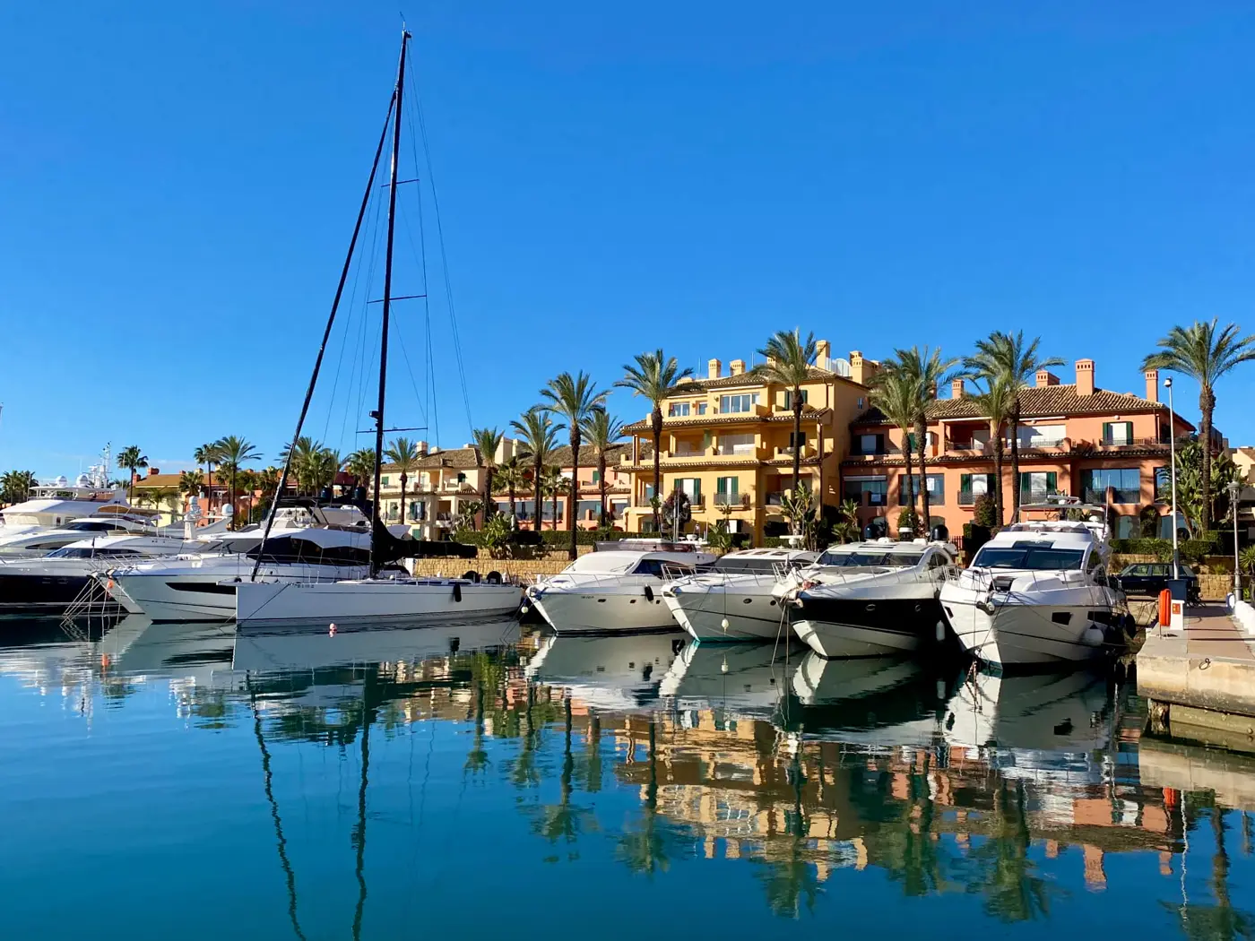 Yachts moored in Sotogrande marina with waterfront apartments behind